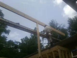 Carpenter setting a ridge beam over a new addition frame — Ice Dam Removal by Roofing Brothers in Kaibeto