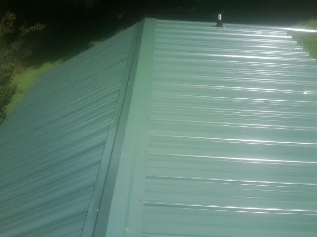 New green metal panels meeting at the ridge of a roof — Flat Roof Repair work by our crew in Kaibeto