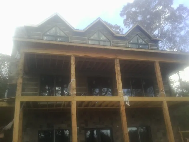Dormers and porch framing on a large log home under construction — Roof Coating work by our crew in Kaibeto