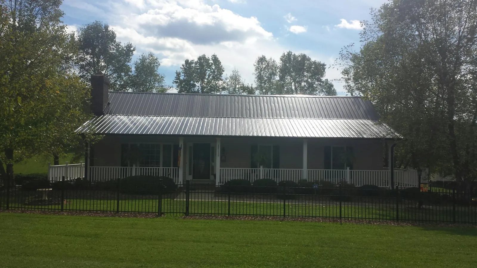 Gray metal roof on a brick ranch with a full width front porch — Gutter Guard Installation work by our crew in Kaibeto