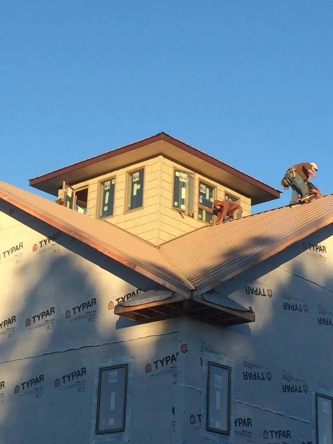 Roofers working around a rooftop cupola on a new metal roof at sunset — Roof Waterproofing in Kaibeto by Roofing Brothers
